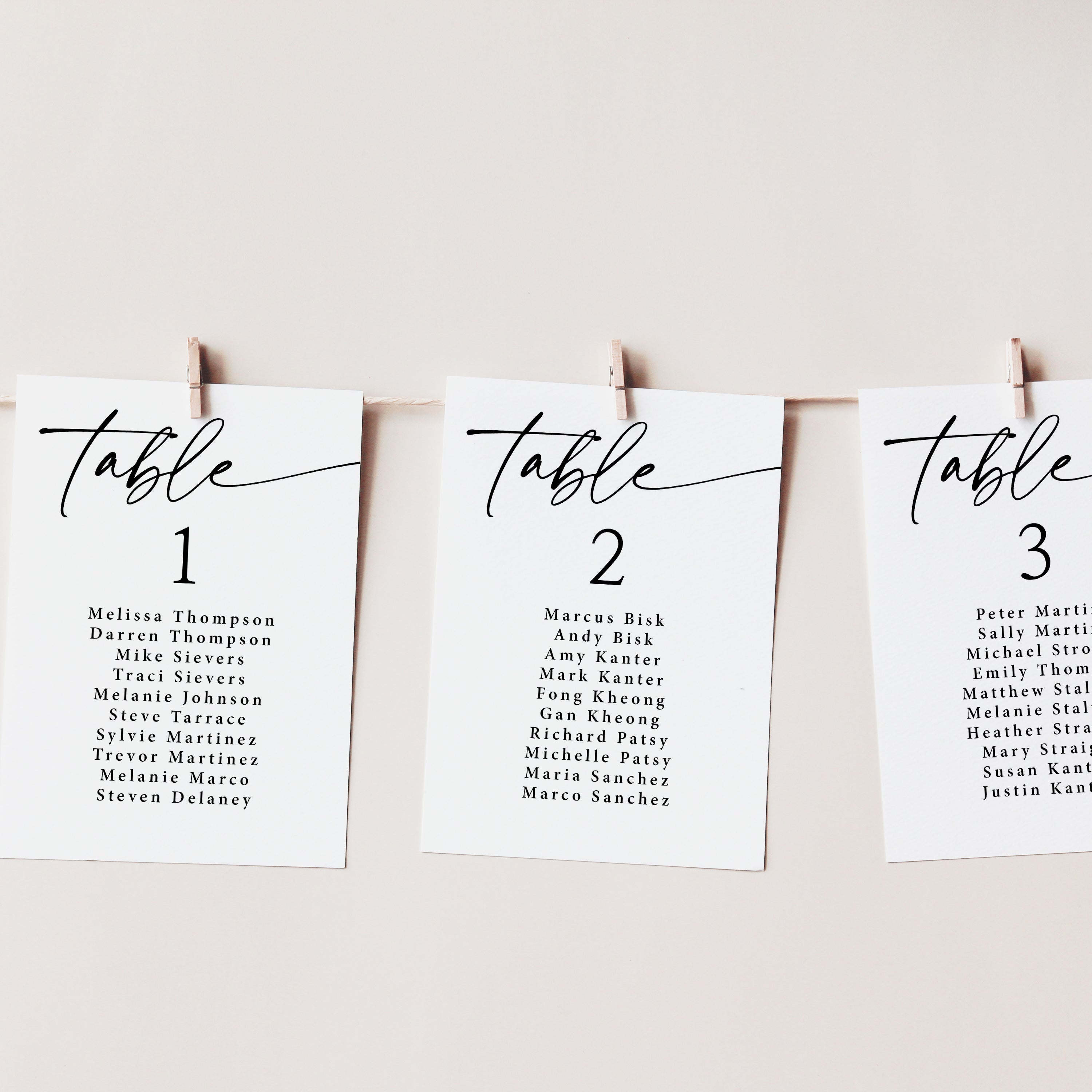 Three black and white seating charts hanging on a string line by clothespins.